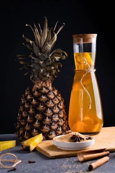 Ananas Tepache. Ferahlatıcı içecek, taze ananas kabuğu ve çekirdekten yapılan hafif mayalanmış içecek, artı kahverengi şeker. Yüksek kalite fotoğraf. Şişe içinde, sade bir şekilde servis edilmiş. Koyu arkaplan.