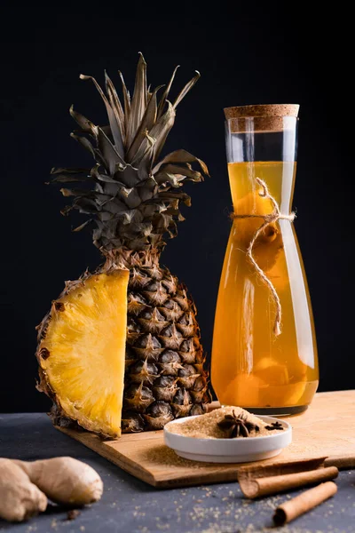 Ananas Tepache. Ferahlatıcı içecek, taze ananas kabuğu ve çekirdekten yapılan hafif mayalanmış içecek, artı kahverengi şeker. Yüksek kalite fotoğraf. Şişe içinde, sade bir şekilde servis edilmiş. Koyu arkaplan.