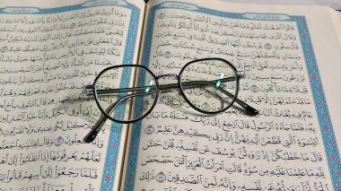 Kediri, INDONEZYA 16 Mart 2025: Açık Kur 'an, Kur' an, El-Kur 'an, Ramazan için İslam arka planı, Kurban Bayramı ve El-Fetih. Beyaz arka planda gözlüklü bir Mekke el yazması.