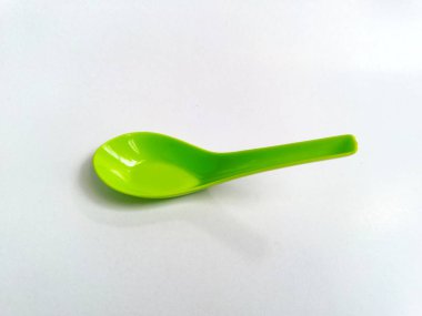 Beyaz arkaplanda izole edilmiş yeşil plastik kaşık kapat