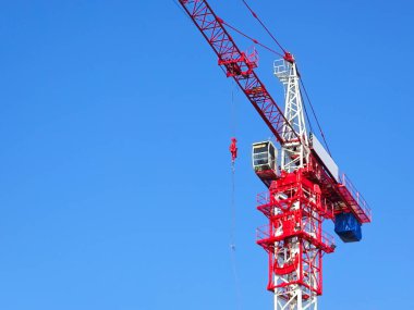 Mavi gökyüzü arka planında ağır ağırlık taşıyan vinç mavi gökyüzünün altında vinç kaldırıyor.