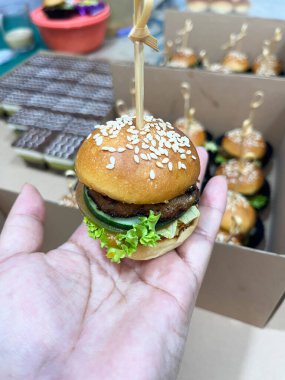 Handheld mini burger with fresh veggies and cheese, skewered for easy serving, perfect for parties, catering, or casual snacking