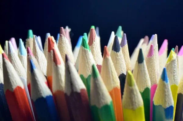Karanlık Üzerine Renkli Kalemler. Keskinleştirilmiş uçlu renkli kalemlerden oluşan bir fotoğraf, koyu bir arkaplan üzerine kurulmuş..