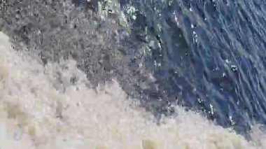 Yüksek açılı bir görüntü, suyun dinamik hareketini bir tekne hareket ederken yakalar ve suyun ana gövdesinin derin maviliğine karşı köpüklü beyaz bir iz bırakır..