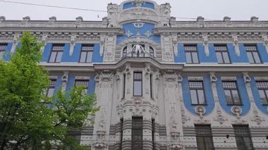 Video, dışavurumcu yüzler ve balkondaki ayırt edici figür de dahil olmak üzere heykel süslemeleriyle tanınan tanınmış bir Art Nouveau binasının ayrıntılı ve benzersiz dış görünüşünü kaydediyor.