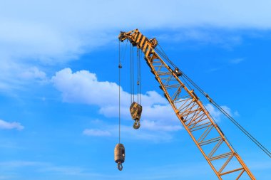 Close-up industrial big crane with steel hook for work on construction building outdoor site on blue sky in daylight, copy space