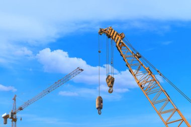 Close-up industrial big crane with steel hook for work on construction building outdoor site on blue sky in daylight, copy space