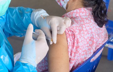Bağışıklık enfeksiyonu Corona virüsü ya da vücut, sağlık ve tıbbi bakımda covid-19 üretimi için yaşlı kadının üst koluna aşı yapan doktorların yakın çekim ve seçici odağı
