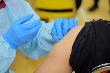 Bağışıklık enfeksiyonu Corona virüsü ya da covid-19 tipi beta, alfa, delta ve omikron üretimi için genç bir adamın üst koluna aşı yapan doktorların yakın çekim ve seçici odağı.