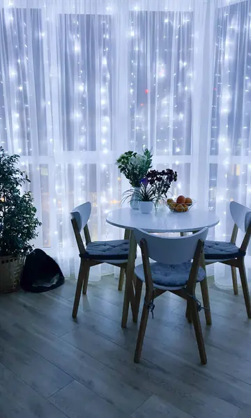 Panoramik pencerede çelenk. Işıkta İskandinav apartmanı