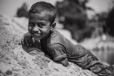 Taherpur, Bangladeş - 05 Kasım 2019: Gülümseyen ve kameraya bakan zavallı çocuğa odaklanın. Uzak bir köydeki fakir bir ailenin tek renkli fotoğrafı..