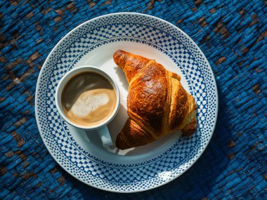 Mavi tabak, kruvasan ve bir fincan.