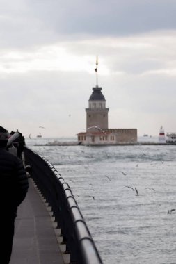 19-01-2024 İstanbul-Türkiye: Deniz feneri ve Martıların Ortasındaki Küçük Ada 'daki Bakire Kulesi
