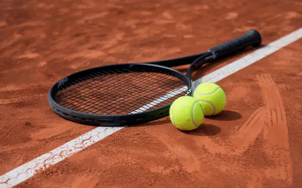 Kil tenis kortunda siyah tenis raketi ve topları