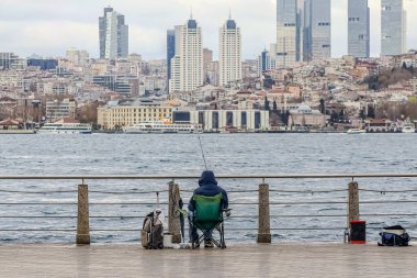 Şehir silueti deniz kenarında yürüyen insanlarla dolu.