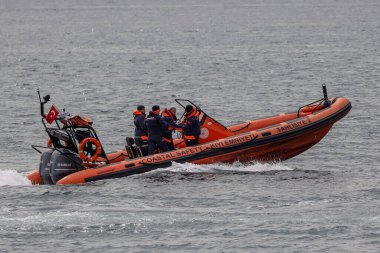 Gri sularda süzülen küçük kırmızı tekne.