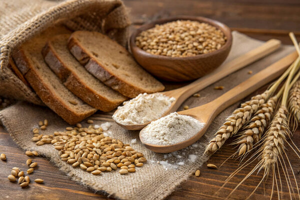 composition of wheat bread and grains of wheat on old wooden background