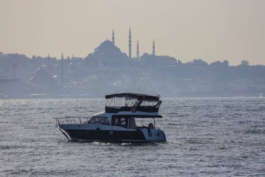 04-10-2024 İstanbul-Türkiye: Arka planda cami siluetiyle Boğaz üzerinde motorlu yat gezisi