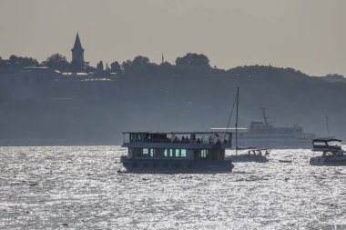 04-10-2024 İstanbul-Türkiye: Günbatımında Topkapı Sarayı ile Boğaz 'da tekne siluetleri