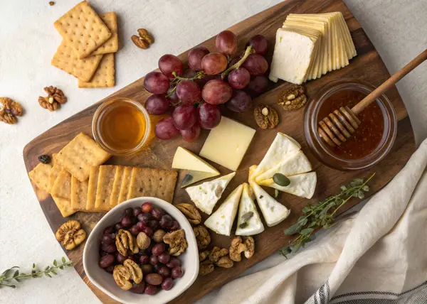 Açık gri arka planda aperatifleri ve abur cuburları olan tahta