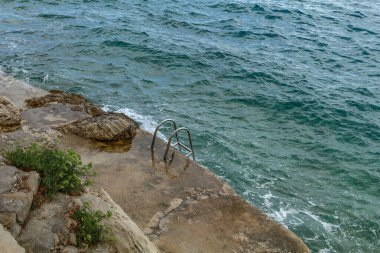 Tehlikeli giriş, keskin ve kaygan taşlar, metal merdiven.