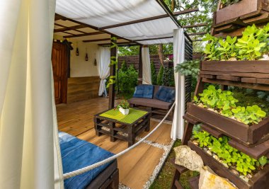 Bahçe terası, dinlenme yeri, ahşap paletler, pergola ve çiçeklerden yapılmış bahçe mobilyaları.