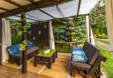Bahçe terası, dinlenme yeri, ahşap paletler, pergola ve çiçeklerden yapılmış bahçe mobilyaları.
