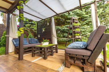 Bahçe terası, dinlenme yeri, ahşap paletler, pergola ve çiçeklerden yapılmış bahçe mobilyaları.