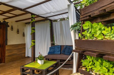 Bahçe terası, dinlenme yeri, ahşap paletler, pergola ve çiçeklerden yapılmış bahçe mobilyaları.