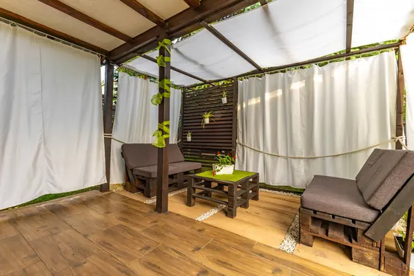 Bahçe terası, dinlenme yeri, ahşap paletler, pergola ve çiçeklerden yapılmış bahçe mobilyaları.