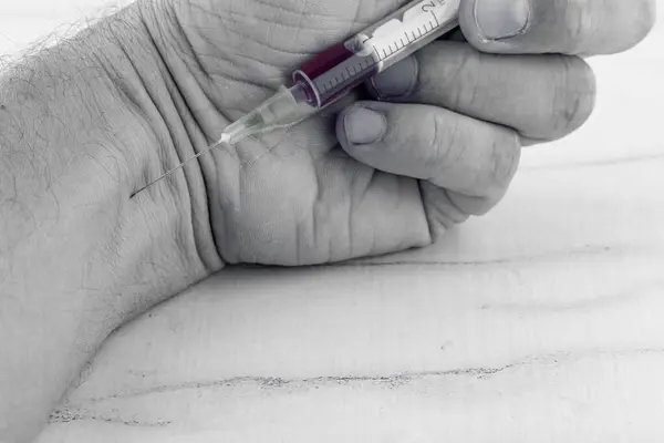Fentanil opioidler morfin Krak ilaçları ve ilaçlar. Bir adam elinde bir şırınga tutuyor ve Han 'ına iğne batırıyor.