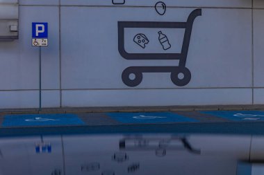 Duvarda alışveriş arabasının logosu var. Engelliler için park yeri var.
