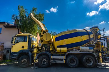 Büyük siyah ve sarı bir beton karıştırıcı bir evin temellerini inşa ederken betonu karıştırır ve döker