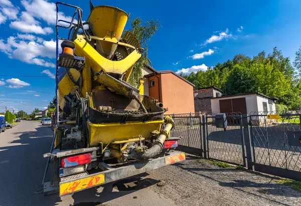 stock image A large black and yellow concrete mixer mixes and pours concrete while building the foundations of a house