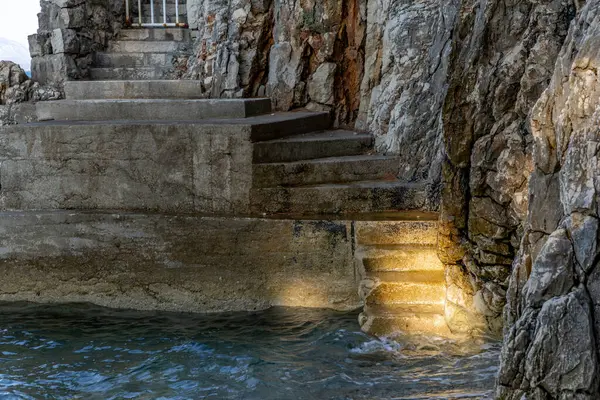 stock image Steep descent down stairs to a rocky beach, Adriatic Sea coast in Croatia, safety railing made of thick fishing rop