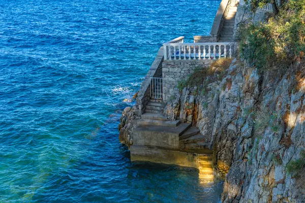 stock image Steep descent down stairs to a rocky beach, Adriatic Sea coast in Croatia, safety railing made of thick fishing rop