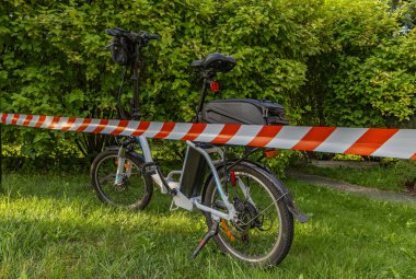 Elektrikli bisiklette bir kaza oldu. Bölge polis tarafından kırmızı ve beyaz musluklarla korunuyor.