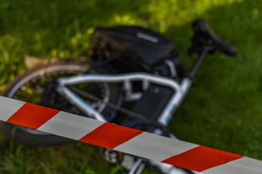 Elektrikli bisiklette bir kaza oldu. Bölge polis tarafından kırmızı ve beyaz musluklarla korunuyor.