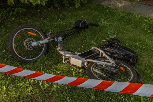 Elektrikli bisiklette bir kaza oldu. Bölge polis tarafından kırmızı ve beyaz musluklarla korunuyor.