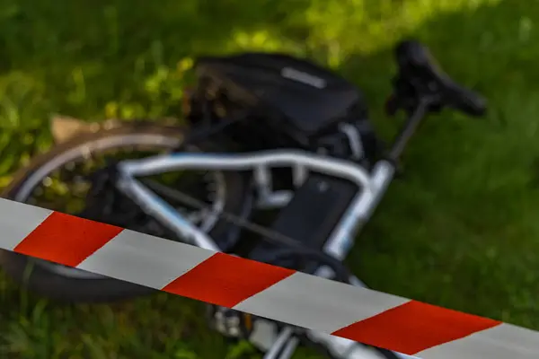 Elektrikli bisiklette bir kaza oldu. Bölge polis tarafından kırmızı ve beyaz musluklarla korunuyor.