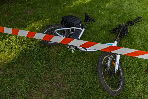 Elektrikli bisiklette bir kaza oldu. Bölge polis tarafından kırmızı ve beyaz musluklarla korunuyor.