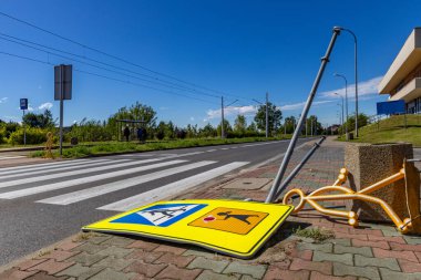 Road accident on the lanes next to a marked pedestrian crossing to school, damaged road sign, reflective figure warning about the pedestrian crossing torn off clipart