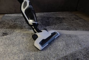 Siyah ve beyaz pille çalışan süpürge, oturma odasındaki kirli halıyı süpürme, daireyi temizleme, tatil için hazırlanma, Noel temizliği.