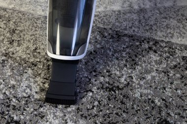 Siyah ve beyaz pille çalışan süpürge, oturma odasındaki kirli halıyı süpürme, daireyi temizleme, tatil için hazırlanma, Noel temizliği.