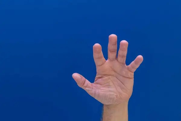 stock image A hand on a blue background of a man calling for help, a symbol, a cry for help, an attempt to stop violence, stop hate on the Internet, at school