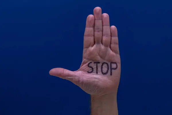 stock image A hand on a blue background of a man calling for help, a symbol, a cry for help, an attempt to stop violence, stop hate on the Internet, at school