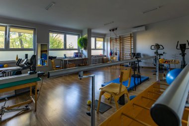 Rehabilitasyon egzersizleri, koşu bandı, rehabilitasyon topları, spor salonu ve tırmanma iskeleti olan bir oda.