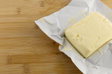 Tahta kesme tahtasındaki bir kalıp taze tereyağı, bir banknot, gıda fiyatlarındaki artış.