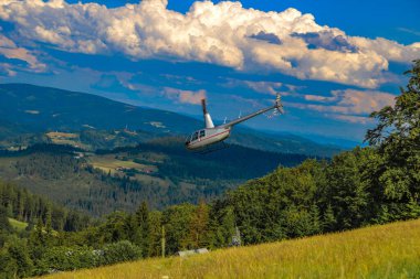 Rescue operation conducted by the mountain rescue service high in the mountains using a small light rescue helicopte clipart