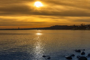 Gdynia Orlowo 'nun renkli manzarası, gün batımı iskelesi, Baltık Se' de yüzen kuğular.